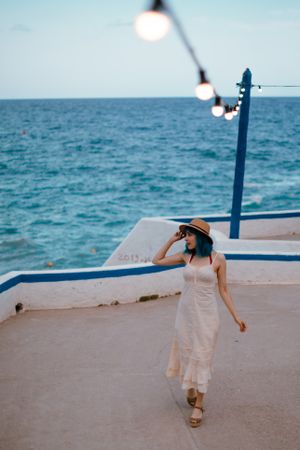 Charming woman in sundress walking along pier