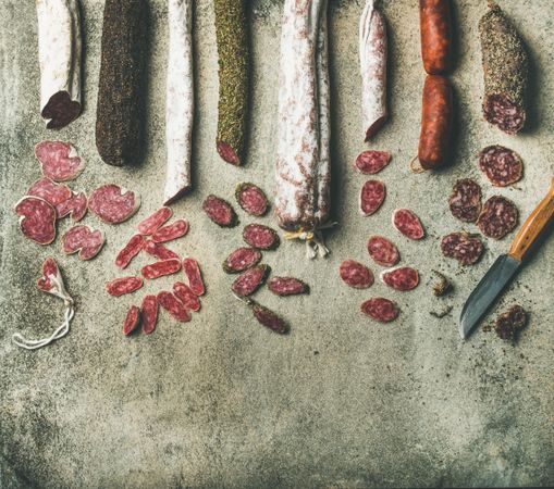 Top view of sliced cured meat sausages beside knife