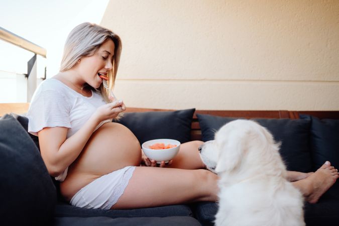 Smiling pregnant woman chilling with dog