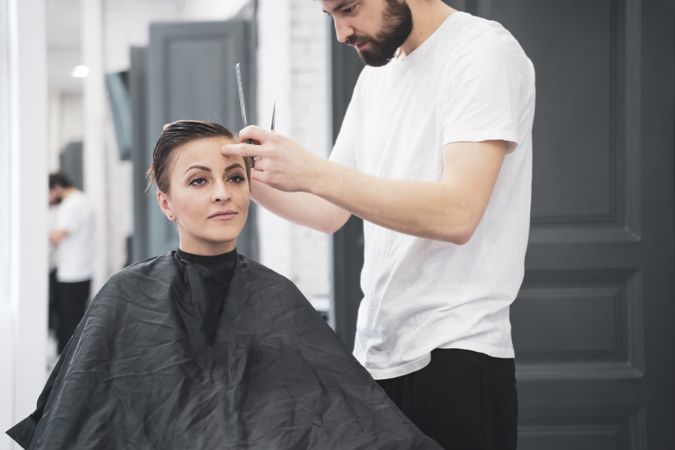 Hairdresser cuts woman's hair with scissors