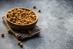 Shelled hazelnuts in bowl on grey counter with copy space