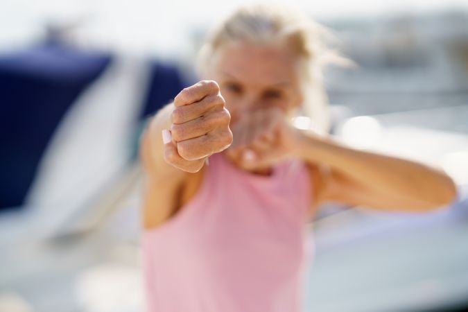 Fist of older woman practicing boxing on a coastal pier