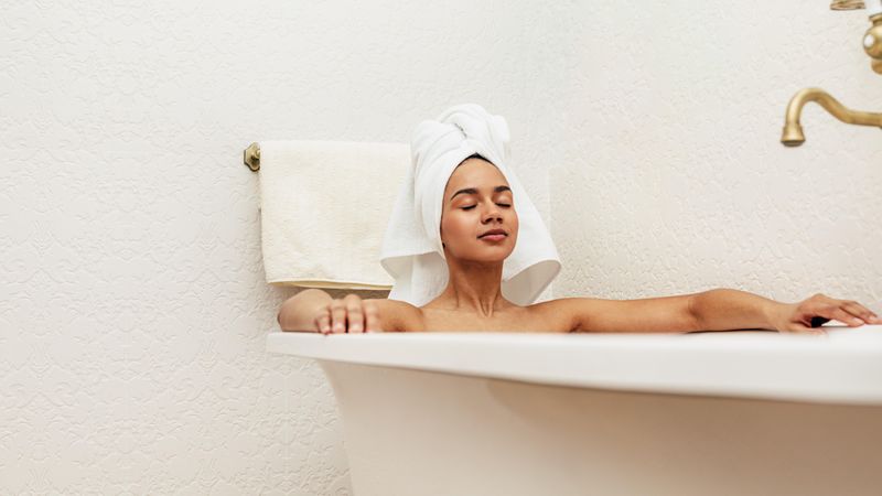 Woman relaxing in bath with towel on head
