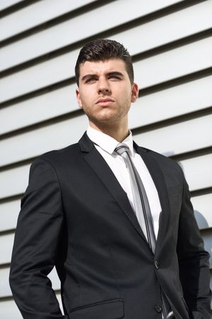 Man in suit standing tall next to wall looking directly at camera