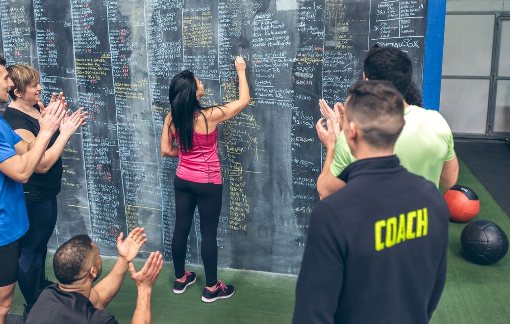 Athlete woman writing down results on the gym board