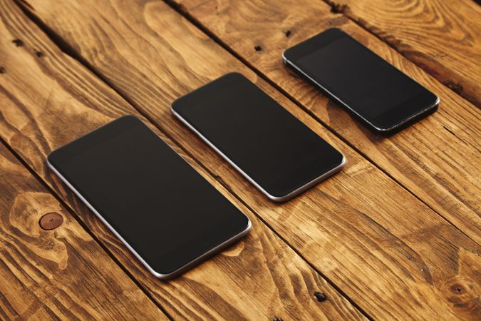 Three phones of different sizes on wooden table
