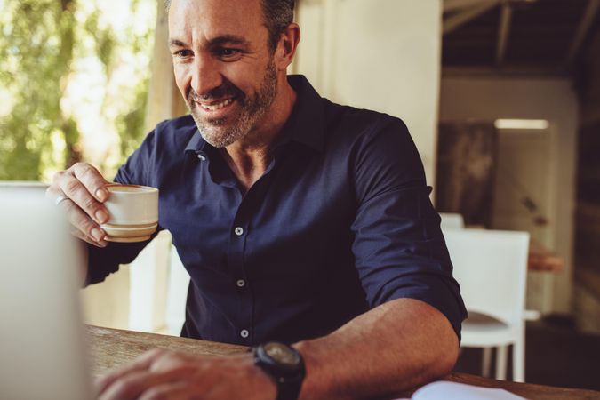 Mature man enjoying coffee while working at a cafe