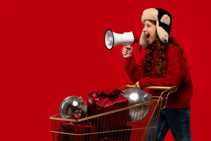 Girl in red sweater and fur hat shouts into megaphone