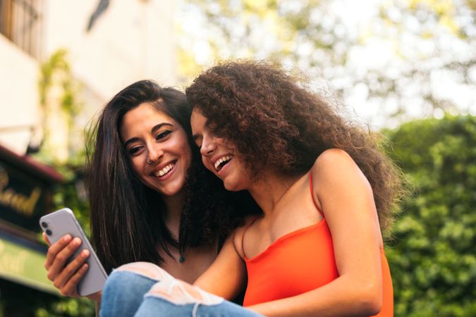 two affectionate women sitting using her mobiles