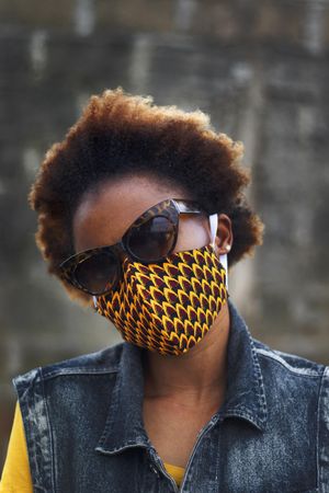 Portrait of a woman in a dark and yellow face mask outdoors