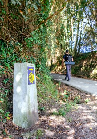Signpost of Saint James way with pilgrim walking