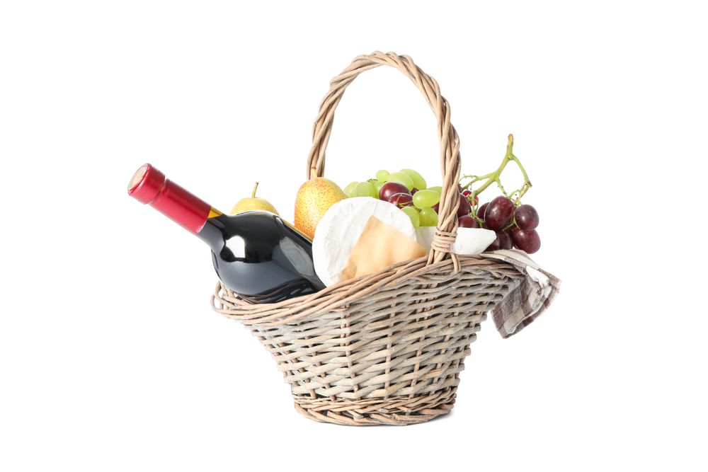 Straw basket with wine, fruits and cheese isolated on plain background
