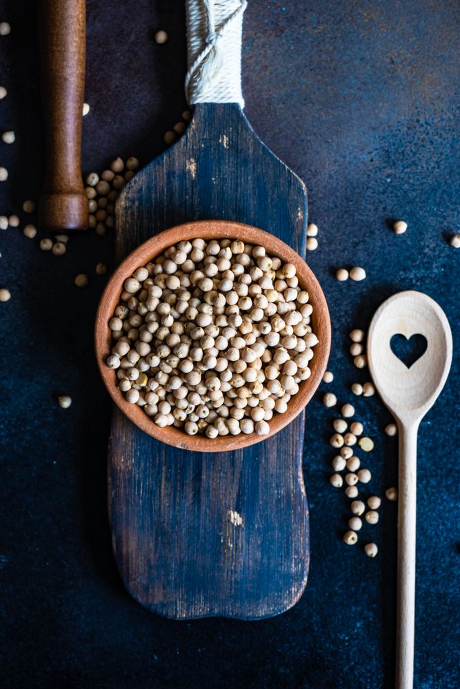 Garbanzo beans in bowl on wooden serving board