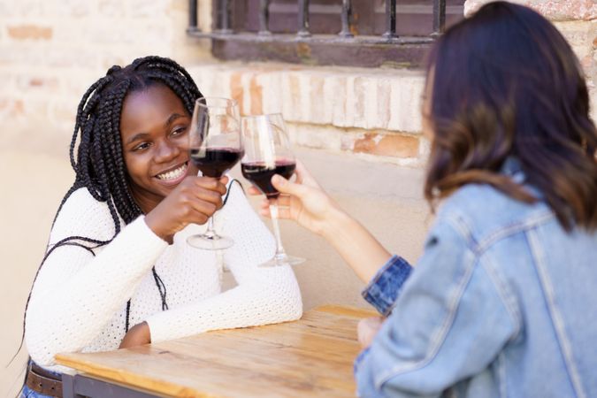 Female friends toasting of red wine at an outdoor table at a restaurant