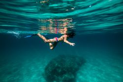Unrecognizable boy snorkeling in mask and flippers in seawater