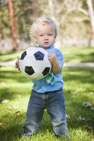 Young Cute Boy Playing with Soccer Ball in Park