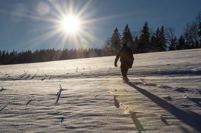 Man rear view climbing through deep snow in mountains
