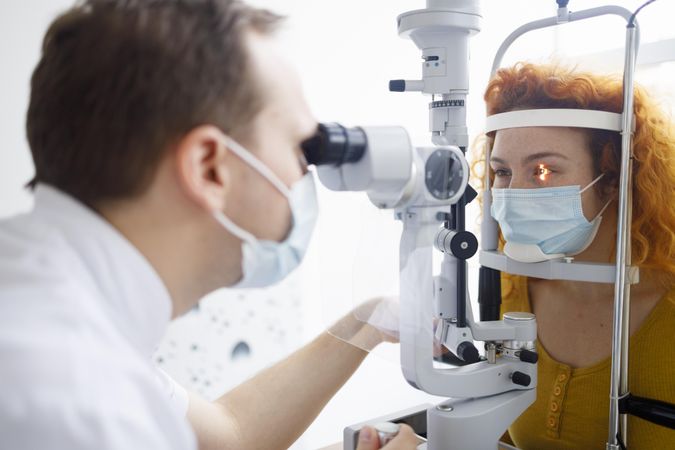 Optometrist looking into patient’s eyes with equipment