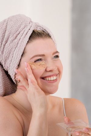 Applying eye patches in skincare routine.