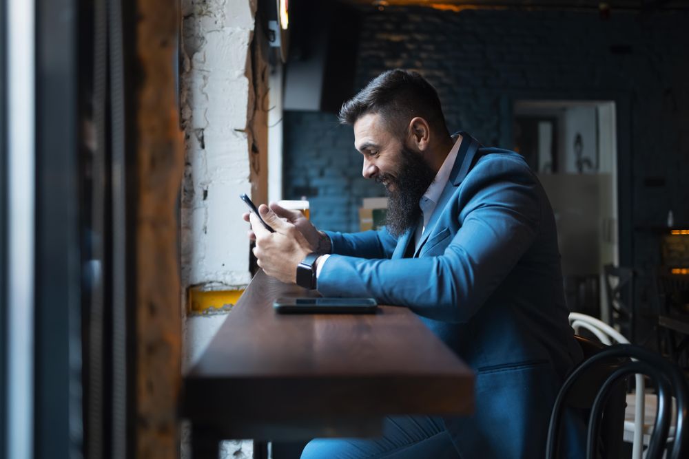 Man laughing at phone in a cafe
