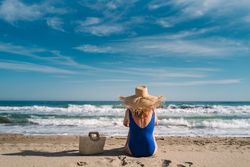 Woman in blue swimsuit and hat on sandy beach