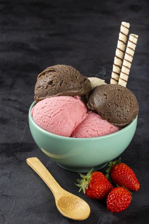 Bowl with Neapolitan ice cream on dark background.