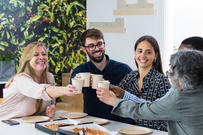 Diverse colleagues having lunch together in kitchen of office