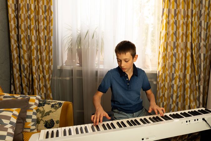 Teen boy in blue polo shirt playing piano