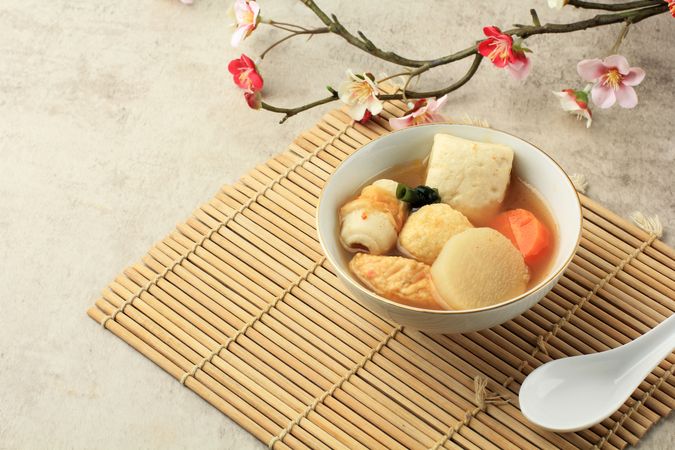 Bowl of Japanese oden served on placemat with flower