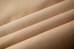 Multi folded light brown fabric background texture.