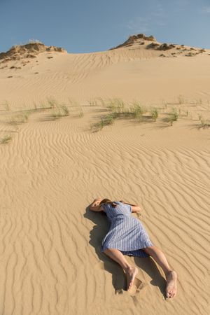 Young woman lying down on sand dune