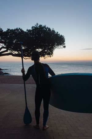 Man practicing paddle surfing with neoprene in a sunrise
