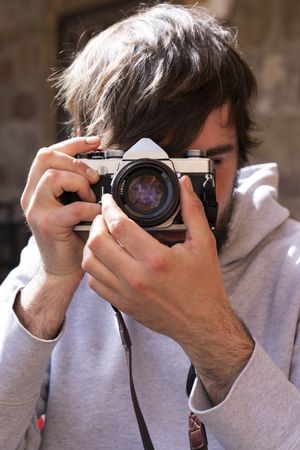 Male photographer taking picture with camera on street