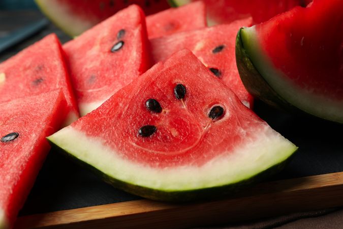 Board with watermelon slices on wooden table, close up