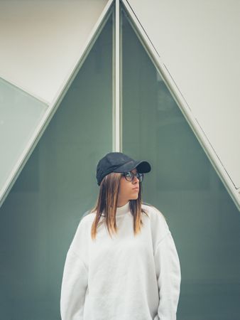 Young woman with glasses standing against wall