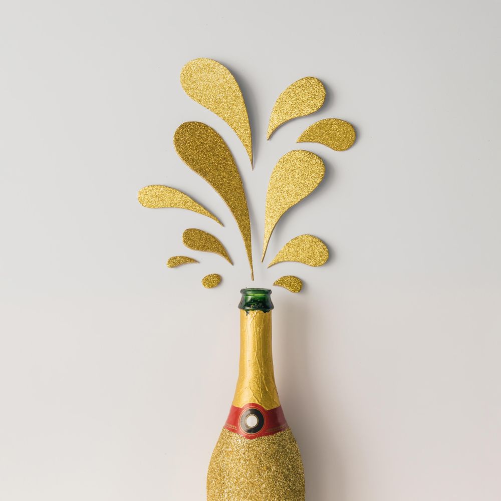 Champagne bottle with golden glittering splashes on light background