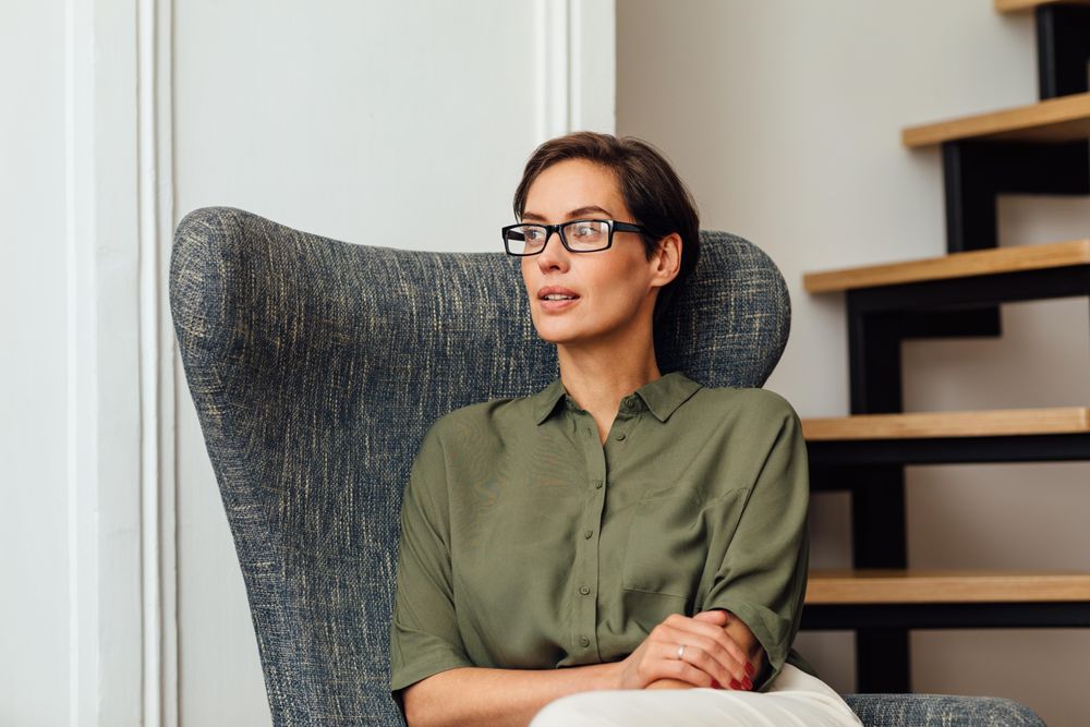 Calm woman sitting in an armchair near the stairs
