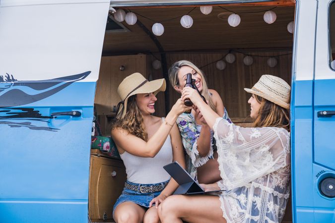 Smiling friends clinking bottles of beer celebrating vacation