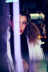 Young woman looking at camera through a purple light flare