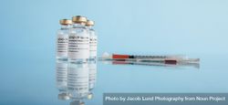 Covid-19 vaccine vials and syringe on reflective surface bemq3b