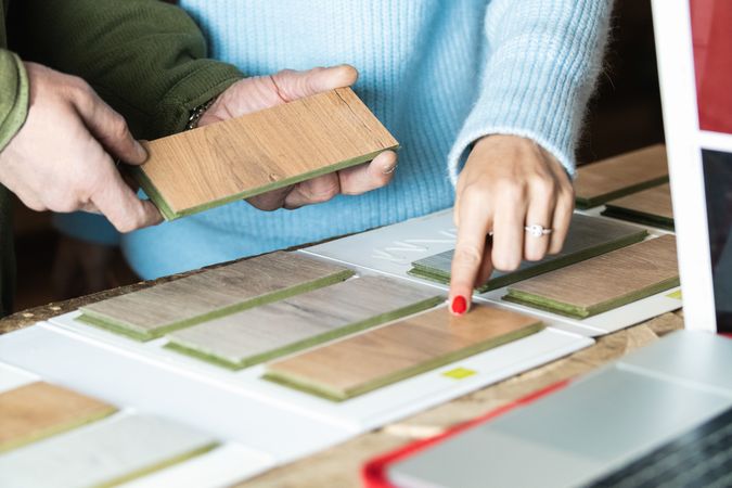 Anonymous woman choosing sample with carpenter in workshop