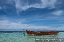 Red boat anchored in shallow tropical waters 0L27r4