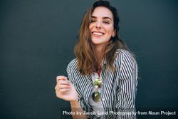 Happy looking woman with striped shirt standing against a wall posing for photograph 0LeYy5