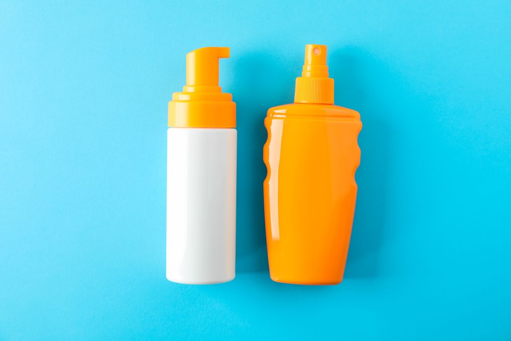 Composition with sunscreen sprays on color background. Space for text, top view