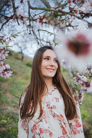 Young happy woman between trees in garden