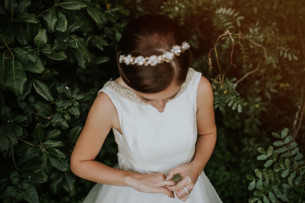 Bride in charming dress admiring finger ring in garden