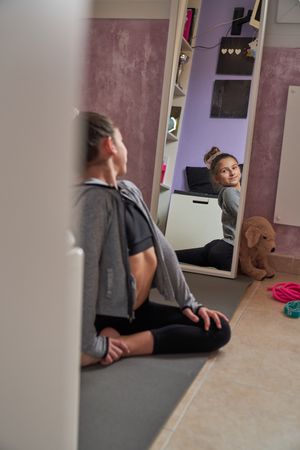 Child stretching legs and looking in mirror at home
