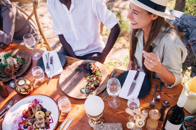 Woman and man sitting at formal outdoor table setting with wine and parsnips