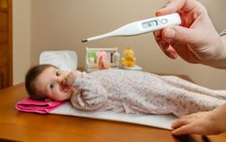 Hands holding thermometer before baby