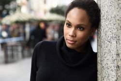 Portrait of calm woman in sweater outside with people in the background, copy space